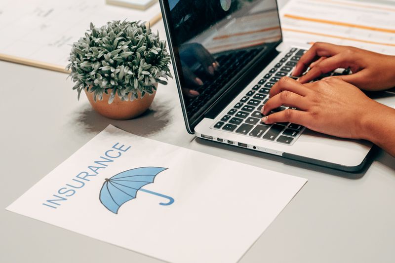 insurance folder and a person using a laptop